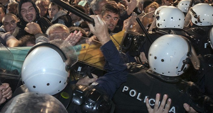 A riot policeman hits Montenegro's opposition leader Nebojsa Medojevic with a baton while dispersing protesters outside the parliament building in the capital Podgorica Montenegro