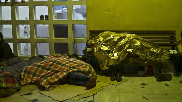 Refugees shelter from the morning cold in the port of Mitylene on the north-east Greek island of Lesbos