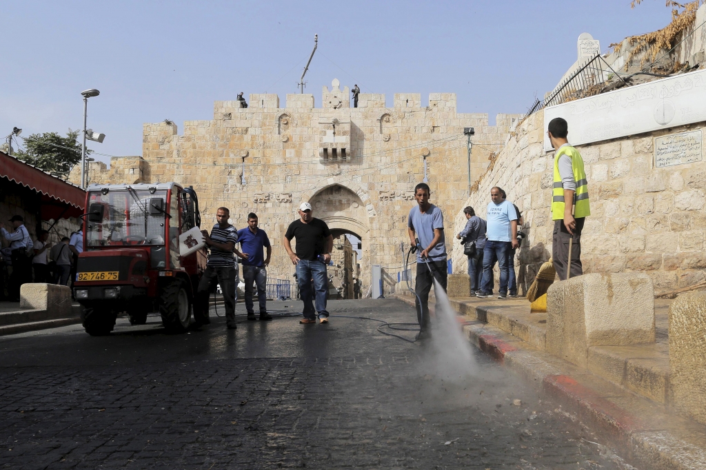 A worker cleans the ground at the scene at the Lions gate of Jerusalem's Old City