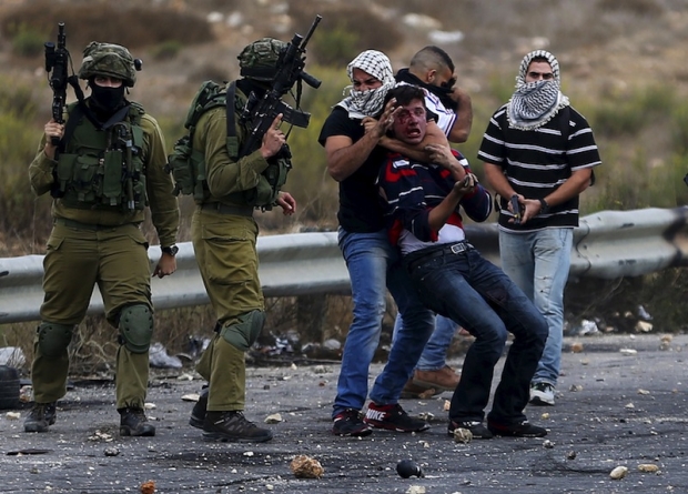 Undercover Israeli security personnel and Israeli soldiers detain a wounded Palestinian protester during clashes near the Jewish settlement of Bet El near the West Bank city of Ramallah