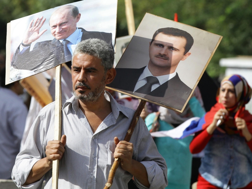 A Syrian man holding portraits of President Bashar Assad and Russian leader Valdimir Putin joins several hundred pro-government demonstrators near the Russian embassy in Damascus on Tuesday to express support for Moscow's air war in Syria. Two rocket