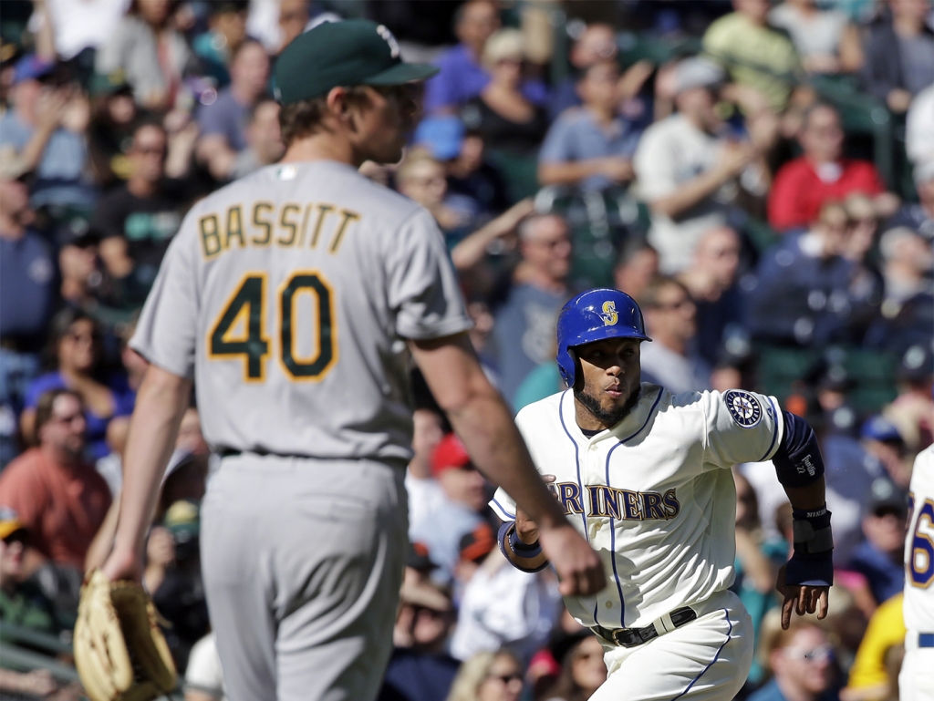 Seattle Mariners&#039 Robinson Cano right heads home to score on a sacrifice fly by Logan Morrison as Oakland Athletics starting pitcher Chris Bassitt looks on during the game Sunday