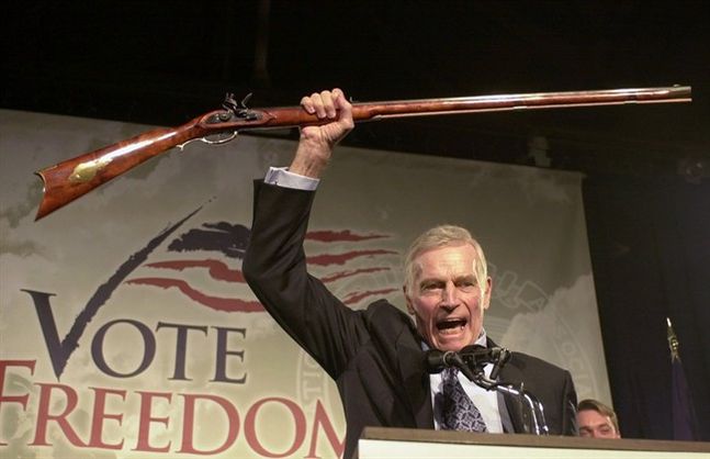 National Rifle Association President Charlton Heston holds up a rifle as he addresses gun owners during