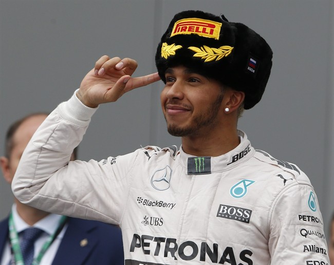 Mercedes driver Lewis Hamilton of Britain celebrates on the podium flanked by Russian President Vlaimir Putin after winning the Formula One Russian Grand Prix at the Sochi Autodrom in Sochi Russia Sunday Oct. 11 2015