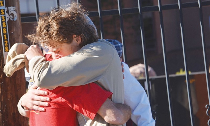 Flagstaff Two people embrace outside a Northern Arizona University student dormitory on Friday after an early morning confrontation between two groups of students escalated into gunfire.—AP