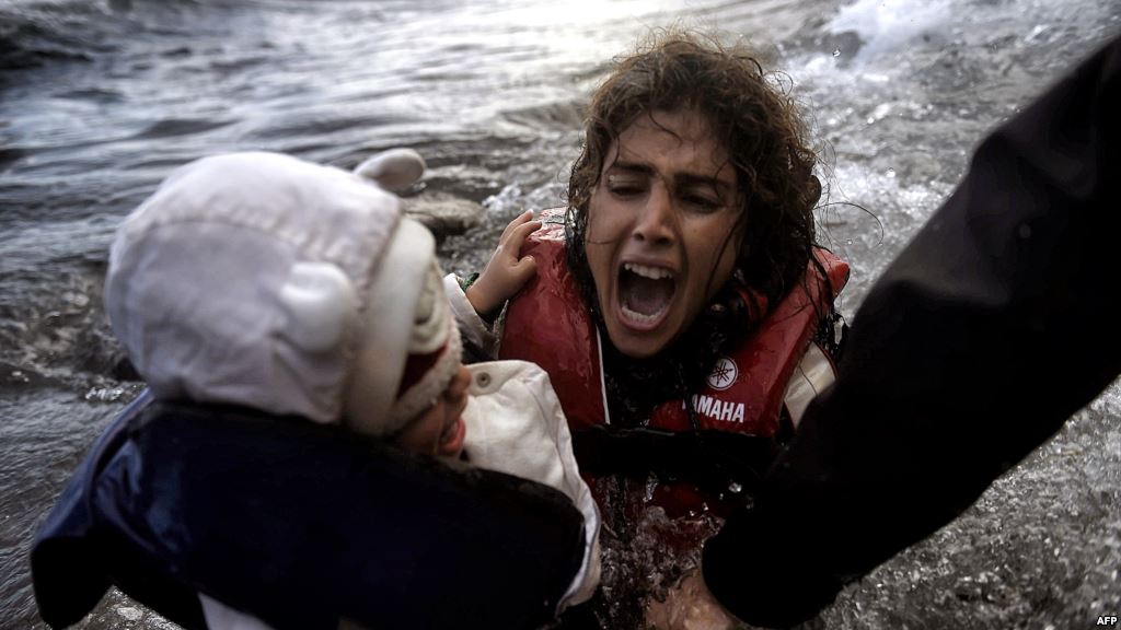 A woman falls into the water with her child as they disembark from a dinghy as refugees and migrants arrive at the Greek island of Lesbos after crossing the Aegean sea from Turkey earlier this month