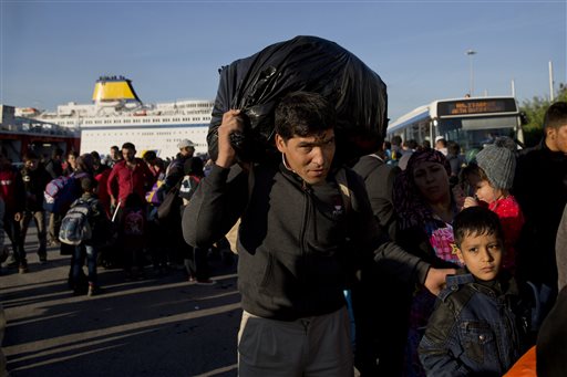 A man carries his belonging upon arriving with his family from the Greek island of Lesbos at the Athens&#039 port of Piraeus Wednesday Oct. 14 2015. The international Organization for Migration said more than 593,000 people have crossed this year