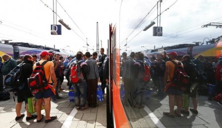 Migrants are reflected in a window as they wait to board a regional train at the main railway station in Munich Germany