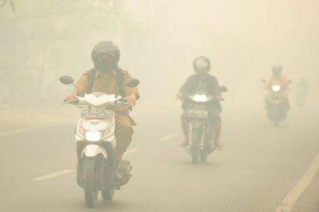 People ride motorcycles as haze shrouds the street in Palangkaraya Central Kalimantan province Indonesia