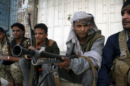 Pro-government militants sit on the side of a street where they fight against Houthi militia men in Yemen's southwestern city of Taiz