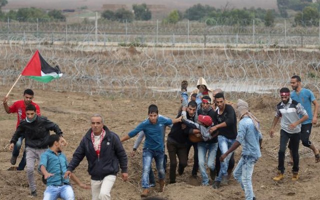 A wounded Palestinian protester is evacuated by comrades during clashes with the Israeli troops on the border between Israel and Central Gaza Strip