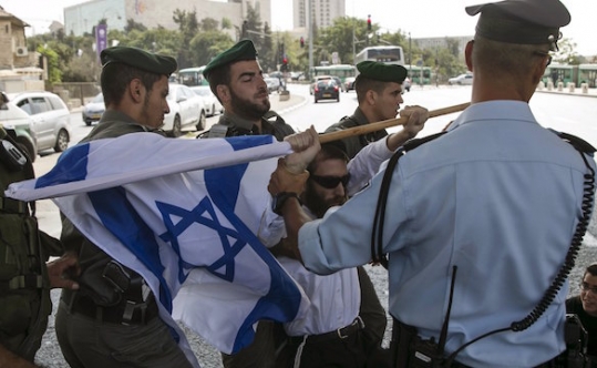 A right-wing Israeli protester is removed by border policemen as he tries to block a street in Jerusalem during a demonstration against the killing of an Israeli couple