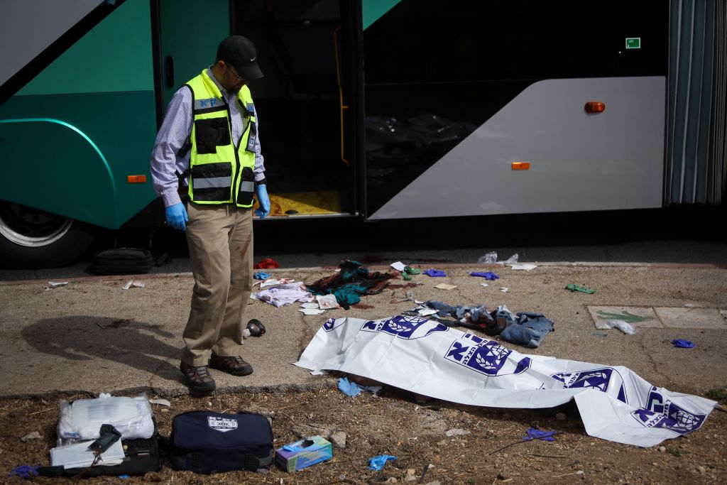 Rescue personnel stand near a victim who was killed in a terror attack in the Armon Hanatziv neighborhood