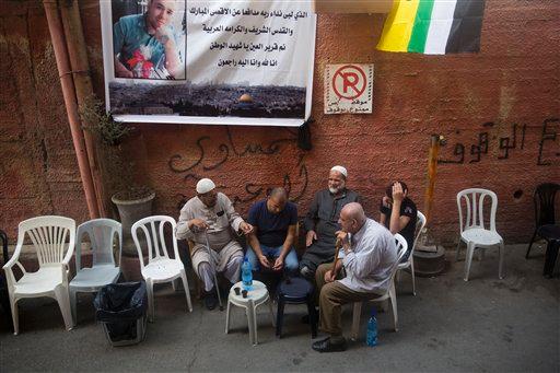 Palestinians sit under a poster showing Mohammed Ali 19 in Shafat refugee camp in Jerusalem. Ali was killed after he stabbed an Israeli policeman on Oct. 10 near Old City's Damascus Gate. The Arabic on the poster rea