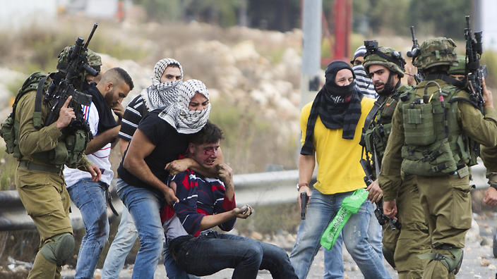 Undercover Israeli police officers and Israeli soldiers detain a wounded Palestinian demonstrator