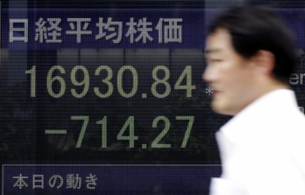 A man walks past an electronic stock board