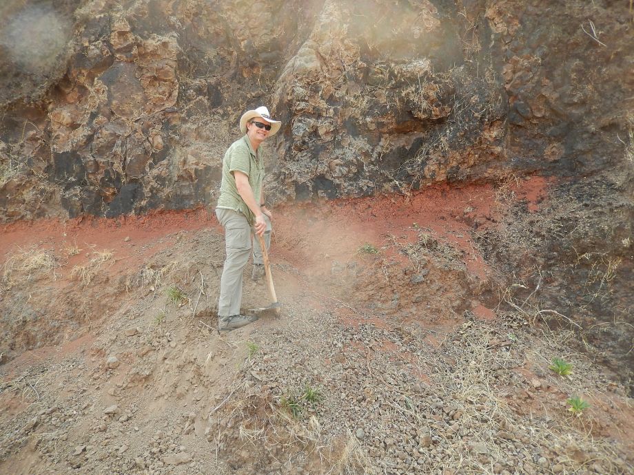 Mark Richards professor of earth and planetary science at UC Berkeley prepares to sample a reddish layer between lava flows. He was the lead researcher of a team of scientist determining a deeper understanding of the timing of volcanic eruptions that