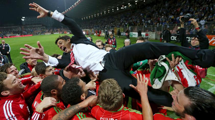 Wales manager Chris Coleman is held up by his players as they celebrate after qualifying for UEFA Euro 2016