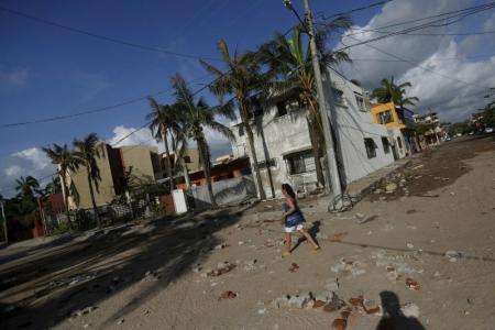 A woman walks along a street damaged by the heavy rains after the passing of Hurricane Patricia in Barra de Navidad Mexico