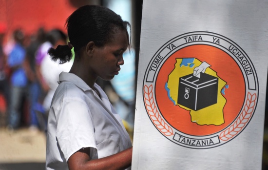 A Tanzanian woman casts her vote for the presidential election in a polling booth on which is written'National Electoral Commission in Swahili at a polling station in Dar es Salaam Tanzania Sunday Oct. 25 2015. Voting has started in Tanzania's gene