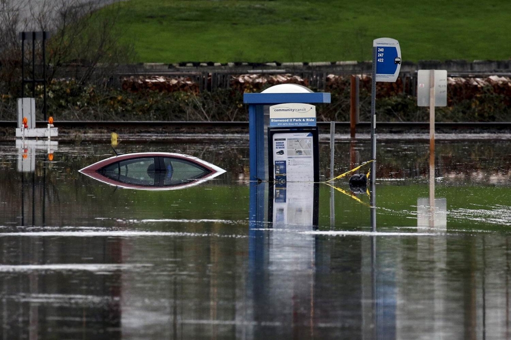 Image A bus stop and a car sit in the flooded waters of the Stillaguamish River in Stanwood Washington