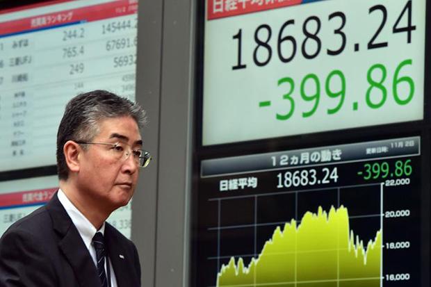 A businessman walks past a share prices board in Tokyo on Monday