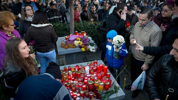 A child holds flowers as people light candles outside the Colectiv nightclub during a mourning march joined by thousands in Bucharest Romania. |AP