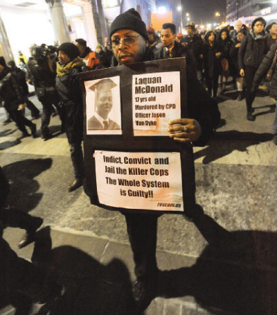 A man holds a sign during a protest for 17-year-old Laquan Mc Donald in Chicago Illinois early Wednesday. — AP