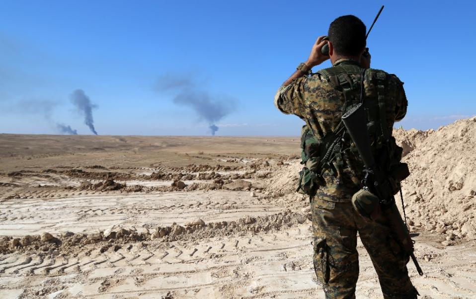 A member of a coalition force monitors the horizon in al-Hawl some 650 kms northeast of Damascus