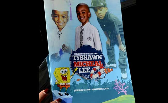 A mourner holds the program for the funeral of 9-year-old Tyshawn Lee at St. Sabina Church Tuesday Nov. 10 2015 in Chicago. The elementary school student was shot in the head Nov. 2 after police say he was lured into an alley and executed because of