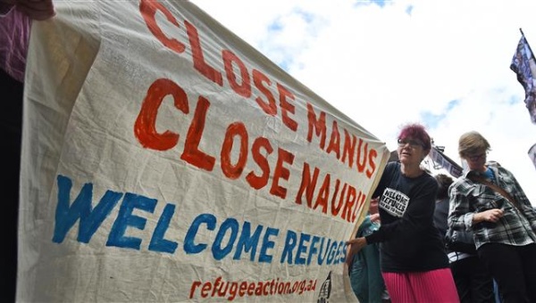 A pro-refugee protester holds up a banner outside the Transfield Services annual general meeting in Sydney