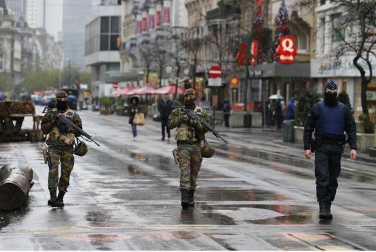 Belgian soldiers and a police officer patrol in central Brussels Saturday. Belgium raised the alert status for its capital to the highest level shutting the metro and warning the public to avoid crowds because of a'serious and imminent threat of an