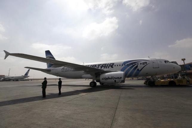 Airport staff stand next to an Egypt Air plane on the runway at Cairo Airport