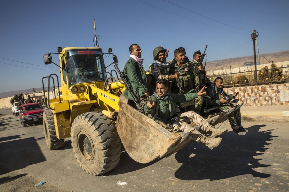 Kurdish fighters known as peshmerga ride in a bulldozer while celebrating the retaking Sinjar Iraq on Friday. Yazidi fighters helped the Kurds regain control of the city from the Islamic State