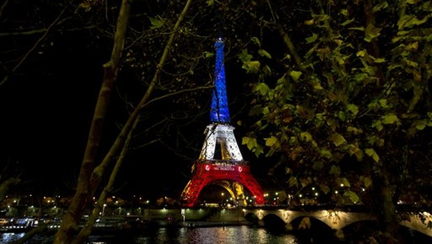 The illuminated Eiffel Tower in the French national colors red white and blue in honor of the victims of the terrorist attacks last Friday and Seine river are seen in Paris | AP