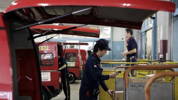 An employee center scans a parcel before loading the package onto a van at a Japan Post Co. post office in Tokyo Japan