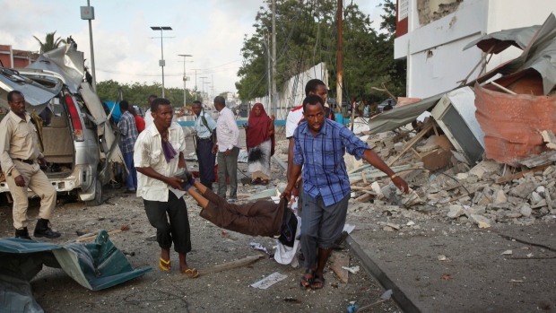 Somali men carry a wounded person to an ambulance outside the Sahafi Hotel in Mogadishu on Sunday after six attackers set off bombs and stormed the compound. The extremist group Al Shabaab claimed responsibility for the assault