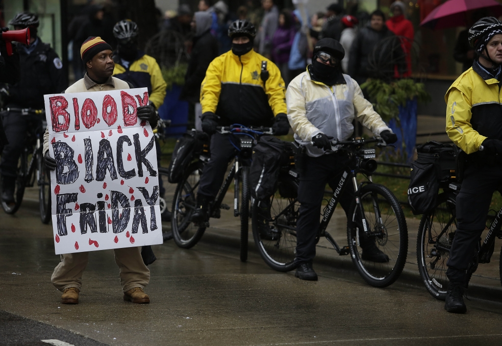 A demonstrator holds a sign as he protest the shooting of Laquan Mc Donald who was killed by a Chicago police Officer along Michigan Avenue also known as the Magnificent Mile