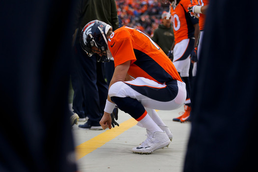 Quarterback Peyton Manning #18 of the Denver Broncos crouches on the sidelines during a game against the Kansas City Chiefs at Sports Authority Field Field at Mile High