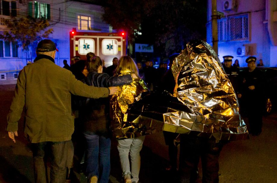 Survivors of an explosion that occurred in a club in Bucharest are led away from the blast scene wrapped in a thermal blanket early Saturday Oct. 31 2015. An explosion and ensuing flames on a stage at a Bucharest nightclub on Friday left more than 20