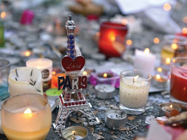 Candles and a miniature Eiffel Tower are placed at a memorial near the Bataclan concert hall