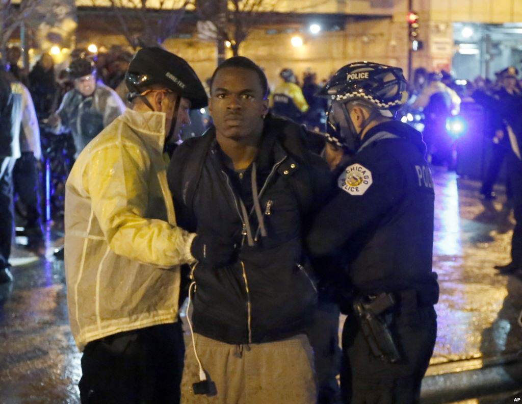 Two Chicago police officers take a man into custody during a protest march Wednesday Nov. 25 2015 in Chicago the day after murder charges were brought against police officer Jason Van Dyke in the killing of 17-year-old Laquan McDonald