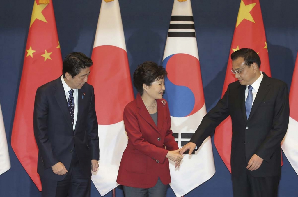 South Korean President Park Geun-hye center offers her hand to shake hands with Chinese Premier Li Keqiang right as Japanese Prime Minister Shinzo Abe watches them at the start of a trilateral summit at the presidential house in Seoul South Korea Su