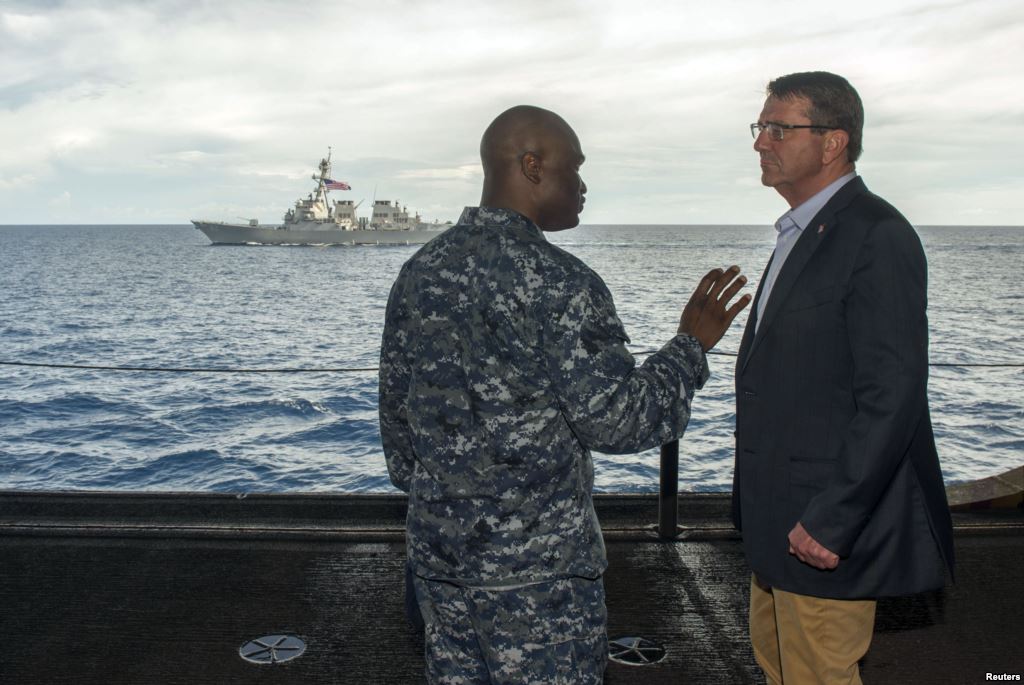 U.S. Secretary of Defense Ash Carter speaks with U.S. Navy Cmdr. Robert C. Francis Jr. as Carter and Malaysian Defense Minister Hishammuddin Hussein visited the USS Theodore Roosevelt aircraft carrier in the South China Sea in this