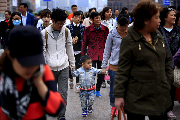 A little boy walks with his parents on a bridge in Shanghai China. The easing of family planning restrictions in China to allow all couples to have two children will benefit around 100 million families a professor told the official China Daily. — Reut