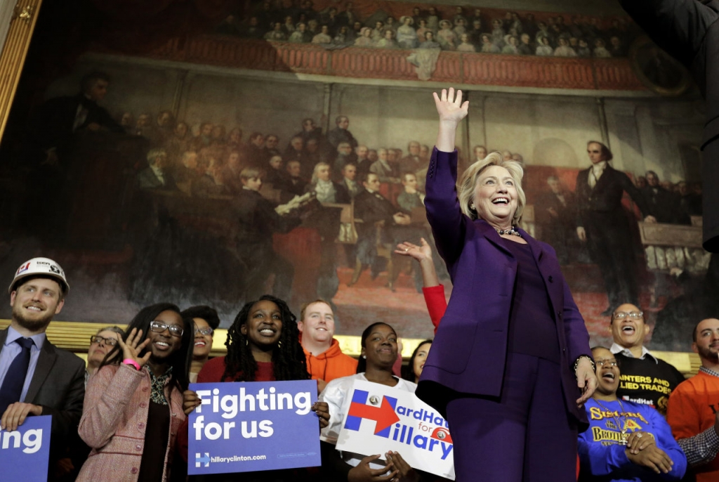 Democratic presidential candidate Hillary Clinton right stands on stage as she greets people at the start of a rally at Faneuil Hall