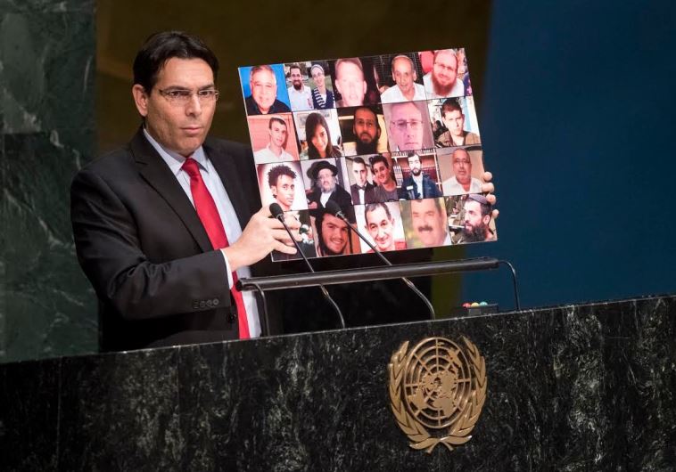 Danny Danon holds up a collage of Israeli victims of Palestinian terrorism. /UN