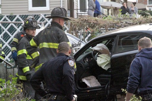 First responders examine an automobile after its driver lost control and plowed into a group of trick-or-treaters in New York Saturday Oct. 31 2015. Three people were killed including a 10-year-old girl. Several others were injured. (AP