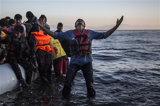 A young man gestures after disembarking from a dinghy at a beach on the Greek island of Lesbos after crossing the Aegean sea from the Turkish coast Saturday Nov. 14 2015. More than 810,000 people have crossed the Mediterranean this year and over 200,0