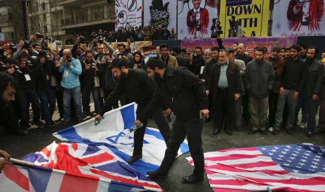 Iranian demonstrators pour gasoline on the U.S. British and Israeli flags to set on fire during an annual rally in front of the former U.S. Embassy in Tehran marking 36th anniversary of the seizure of the embassy by militant Iranian students Wednesday